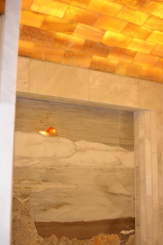 Lighted onyx masterbath shower niche with backlit onyx ceiling tiles and amber stone accents