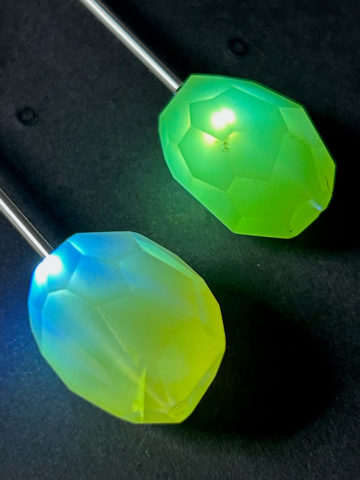 Two large faceted opalite stones glowing green and blue from micro-LED illumination against dark background